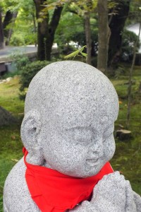 Sinnbild für die Verbundenheit von Natur und Religion: Eine Gottesanbeterin auf dem Haupt einer Jizo-Statue
